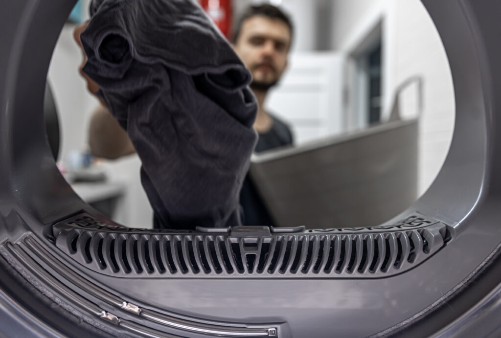 man holding dirty cloth hand view inside washing machine
